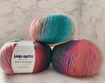 May include: Three balls of yarn in different color combinations. The yarn is a gradient of pink, teal, and green. The label on one ball reads "Lana Gatto" and "Park Avenue".