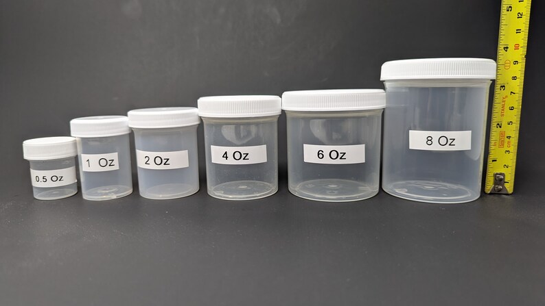 May include: A set of six clear plastic jars with white lids. The jars are labeled with their volume in ounces: 0.5 oz, 1 oz, 2 oz, 4 oz, 6 oz, and 8 oz.