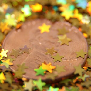 May include: A copper-colored penny coin surrounded by gold glitter stars. The coin has the year 2014 printed on it.