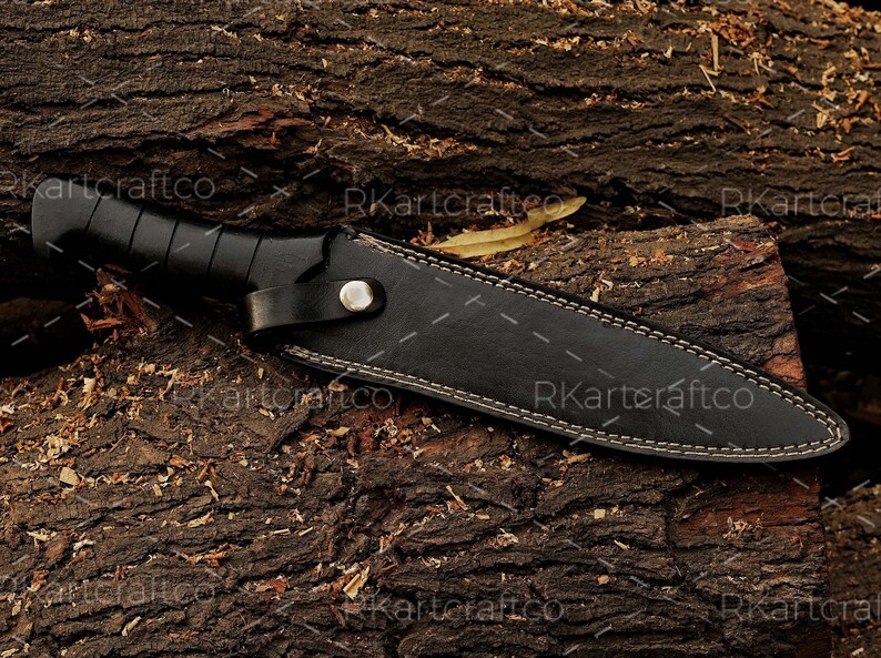 May include: A black leather knife sheath with white stitching detail. The sheath is lying on a piece of rough-hewn wood.