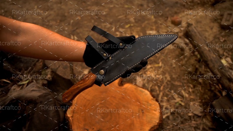 May include: A black leather sheath with a wooden handle knife. The knife is held in the hand of a person.