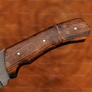 May include: Close-up of a wooden knife handle with a dark brown finish. The handle has a slight curve and is decorated with three brass accents. The handle is made of wood with a natural grain pattern.