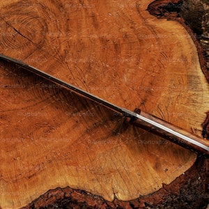 May include: A long, silver-coloured knife with a wooden handle. The knife is lying on a wooden surface.