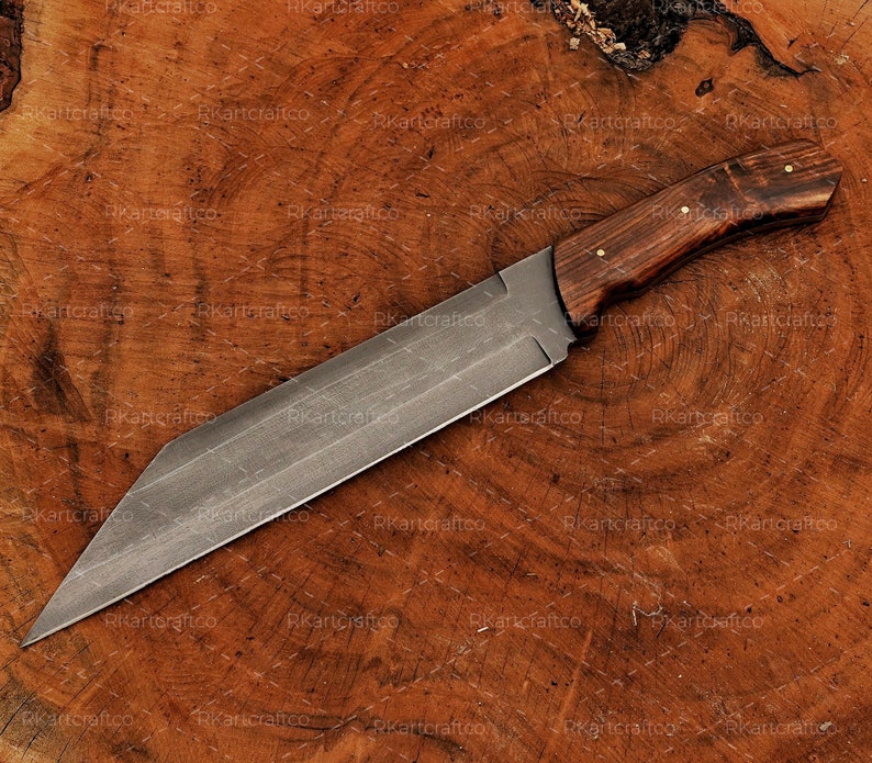 May include: A long, sharp, silver knife with a wooden handle. The handle is dark brown with a light brown grain pattern. The knife is lying on a wooden surface.