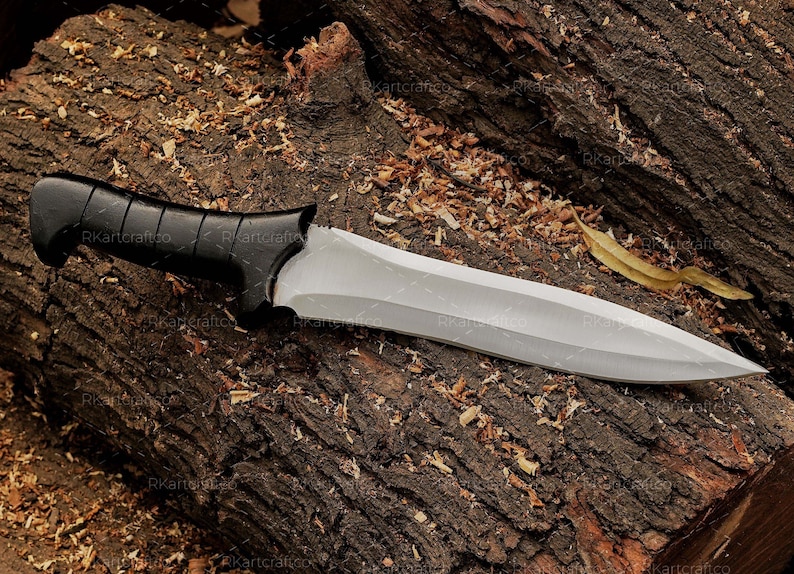 May include: A silver knife with a black handle, lying on a brown wooden surface. The knife has a sharp point and a straight edge.