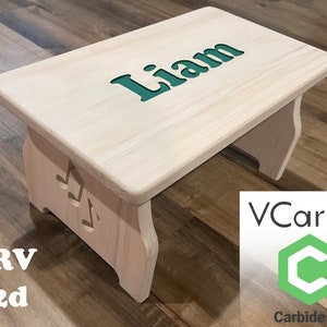 Finished picture of a single step children's step stool that is stained white, and a greenish blue inlayed text with the name 'Liam' on the top of the stool. The sides have music notes on them and text listing .crv, .c2d file extensions.