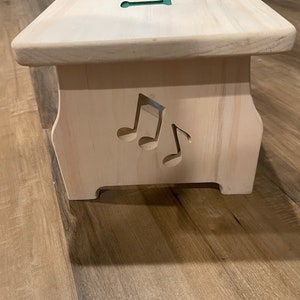 Left side of a white stained single step children's step stool with music notes cut into the side with a CNC machine.