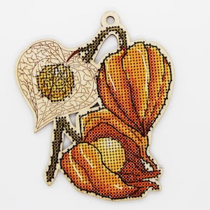 Könnte beinhalten: Ein Holzornament mit einem Kreuzstichdesign einer chinesischen Lampionblume. Das Ornament hat ein herzförmiges Blatt und zwei orangefarbene, laternenartige Kapseln. Der Kreuzstich verwendet Orange-, Gelb- und Brauntöne, mit einem natürlichen Holzuntergrund.