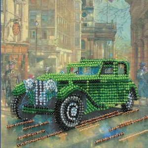 May include: A beaded artwork depicting a vintage green car driving on a city street. The car is the focal point, detailed with green beads, and set against a backdrop of buildings and figures. The artwork is framed.