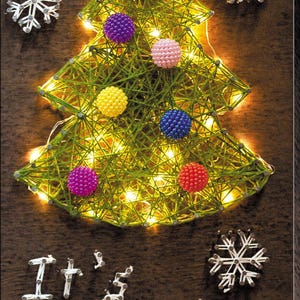 May include: A handmade Christmas tree made of green thread, adorned with colorful beaded ornaments and twinkling lights. The words "It's snowing" are spelled out below the tree with white thread. Two snowflake decorations are also present.