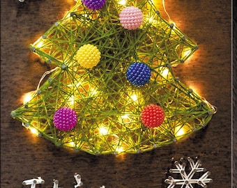 May include: A handmade Christmas tree made of green thread, adorned with colorful beaded ornaments and twinkling lights. The words "It's snowing" are spelled out below the tree with white thread. Two snowflake decorations are also present.