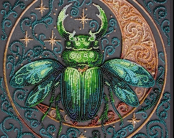 Può includere: Un'opera d'arte dettagliata e perlata raffigurante uno scarabeo verde con ali iridescenti, su sfondo grigio. Lo scarabeo è centrato all'interno di una luna crescente dorata e circondato da volute turchesi e stelle dorate. Il pezzo ha un aspetto strutturato e fatto a mano.