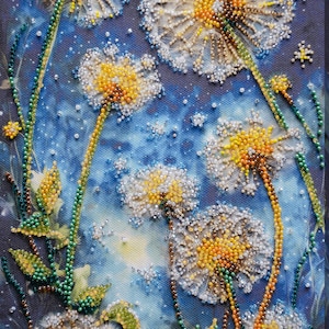 May include: A close-up of a beaded artwork depicting a cluster of white and yellow dandelions with green stems and leaves against a blue background.