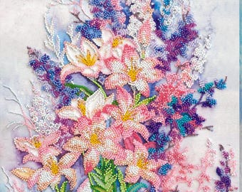 May include: A beaded floral artwork depicting a bouquet of lilies and other flowers in shades of pink, white, purple, and blue. The flowers have yellow centres and green leaves, set against a soft, watercolour-like background.