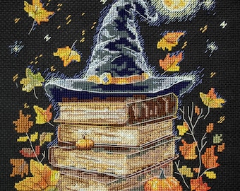 May include: A witch's hat sits atop a stack of books with pumpkins and fall leaves scattered around the base. The hat is blue and gray with a gold band. The books are brown and have gold lettering. The pumpkins are orange and the leaves are red, orange, and yellow. The background is black with a full moon and stars.