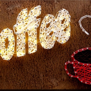 May include: A wooden sign with the word "COFFEE" spelled out in white string art with yellow lights. A red string art coffee cup with a heart-shaped steam design is also featured.