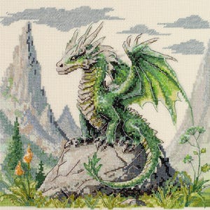 May include: Cross-stitch depicting a green dragon on a rock, with wings extended. The dragon is detailed, with green and grey hues. The background shows mountains and a cloudy sky, with some greenery in the foreground. The artwork is on a cream-colored fabric.