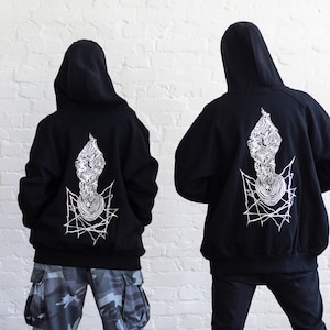 May include: Two black hooded sweatshirts with a white graphic design on the back. The design features a geometric pattern with a spiral in the center.
