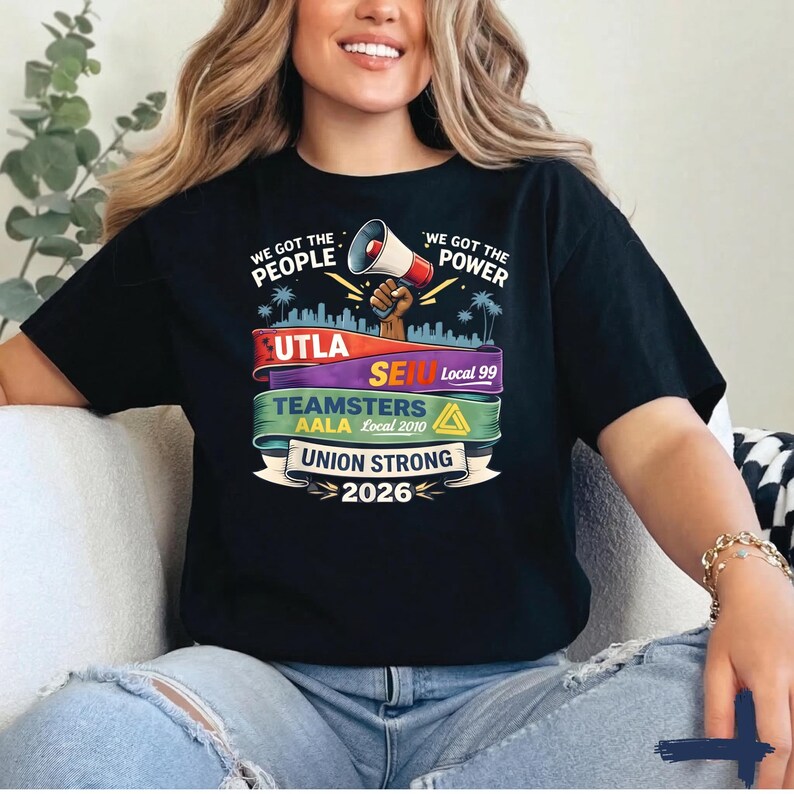 May include: Black t-shirt with the text "WE GOT THE PEOPLE" and "WE GOT THE POWER". The shirt features a graphic of a megaphone, a cityscape, and the words "UTLA", "SEIU", "TEAMSTERS", and "UNION STRONG 2026".