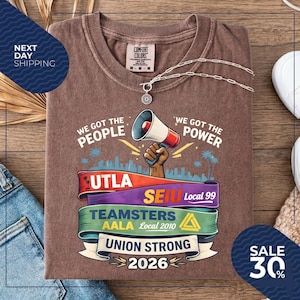 May include: Brown t-shirt with a graphic featuring a megaphone, the words "We Got The People" and "We Got The Power", and union logos. The shirt also has the text "Union Strong 2026".