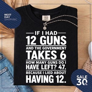 May include: A black t-shirt featuring white text that reads: IF I HAD 12 GUNS AND THE GOVERNMENT TAKES 6 HOW MANY GUNS DO I HAVE LEFT? 47. BECAUSE I LIED ABOUT HAVING 12. The shirt has a Comfort Colors brand label at the inner neckline.