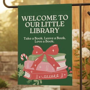 May include: A green garden flag with the text "WELCOME TO OUR LITTLE LIBRARY" and "Take a Book. Leave a Book. Love a Book." A stack of books with a red bow and candy cane is featured.