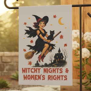 Puede incluir: Una bandera de jardín con una ilustración retro de una bruja en una escoba con un gato negro. La bandera muestra el texto "Witchy Nights & Women's Rights" en naranja. El diseño incluye una casa embrujada, una luna creciente y hojas de otoño.