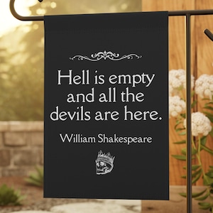 Può includere: Bandiera da giardino nera con la citazione "L'inferno è vuoto e tutti i diavoli sono qui" di William Shakespeare. La bandiera presenta un teschio con una grafica a corona. La bandiera è su un supporto in metallo nero in un giardino.