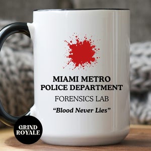 Könnte beinhalten: Weißer Keramikbecher mit schwarzem Griff und Rand. Der Becher zeigt den Text "MIAMI METRO POLICE DEPARTMENT FORENSICS LAB" und den Satz "Blood Never Lies" mit einer roten Blutspritzer-Grafik. Der Becher hat ein "Grind Royale"-Logo.