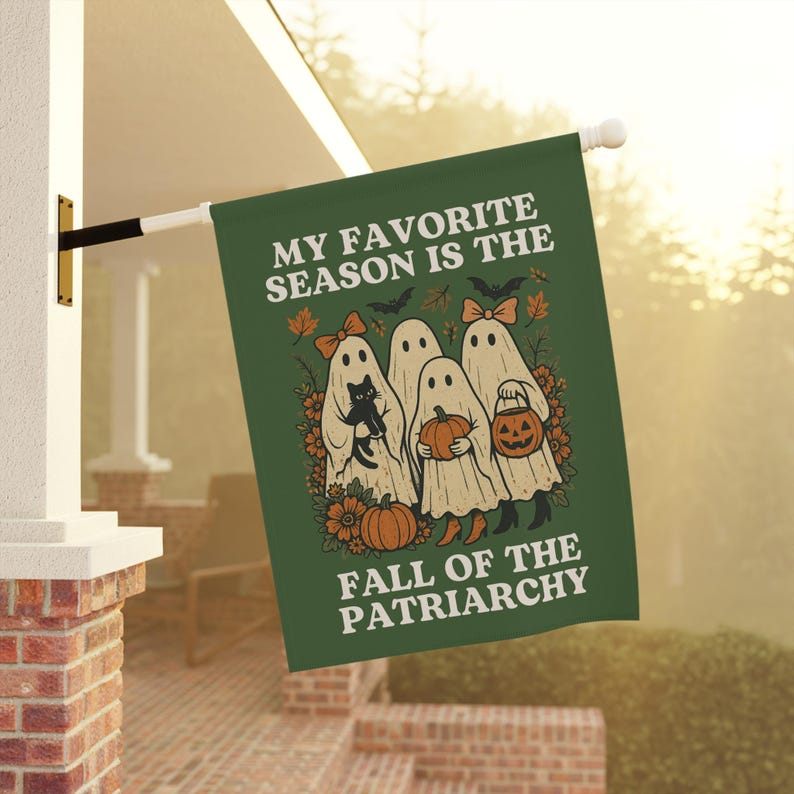 May include: Green Halloween flag with the text "MY FAVORITE SEASON IS THE FALL OF THE PATRIARCHY." The flag features illustrations of ghosts, pumpkins, bats, and fall foliage. A black cat is held by one of the ghosts.