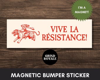 May include: A rectangular magnetic bumper sticker with a cream background and red text that reads VIVE LA RÉSISTANCE! next to a red illustration of a person riding a tiger. A green starburst graphic says I'M A MAGNET! and a black circle says GRIND ROYALE.