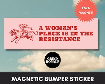 May include: A pink and red magnetic bumper sticker with a woman riding a tiger and the text "A woman's place is in the resistance". The sticker also has the text "I'm a magnet!" and "Grind Royale" in the bottom right corner.