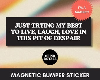 Puede incluir: Una pegatina magnética negra para parachoques con el texto "JUST TRYING MY BEST TO LIVE, LAUGH, LOVE IN THIS PIT OF DESPAIR". Una pegatina roja en forma de estrella dice "I'M A MAGNET!". También es visible el logotipo de Grind Royale.