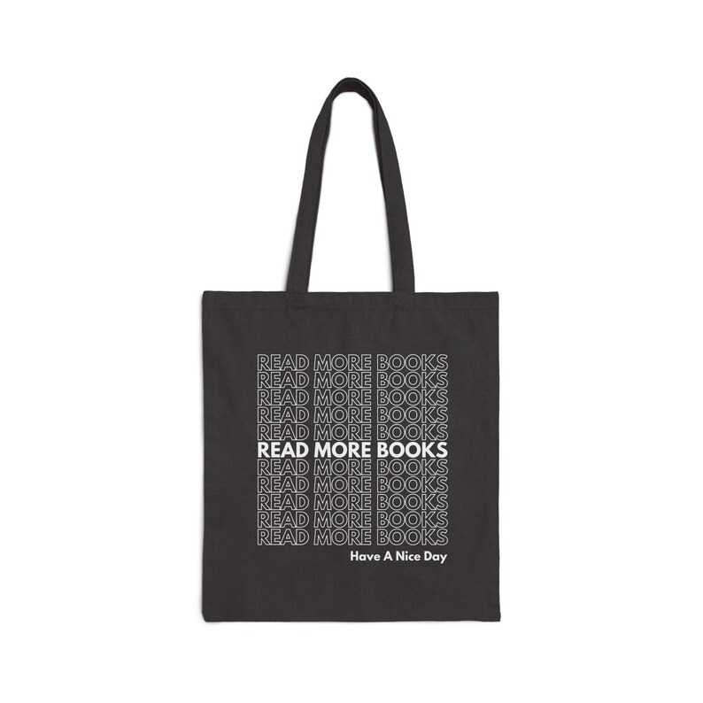 May include: Black tote bag with the text "READ MORE BOOKS" repeated multiple times in white. The text is in a retro font style. The bottom of the bag says "Have A Nice Day".