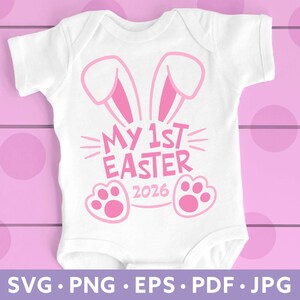 May include: White baby onesie with pink bunny ears, the text "MY 1ST EASTER 2026", and paw prints. The onesie is on a pink wooden background. The bottom of the image has the text "SVG • PNG • EPS • PDF • JPG".