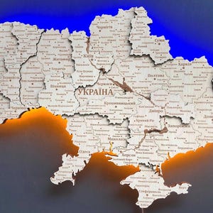 May include: Wooden map of Ukraine with city names, illuminated with blue and orange lights. The word "UKRAINA" is prominently displayed. A decorative piece for home decor.