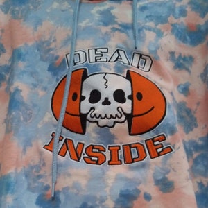 May include: A blue and pink tie-dye hoodie with the text "DEAD INSIDE" in orange and black lettering. A skull with a cracked smile is inside a smiley face.