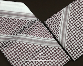 May include: A white and brown patterned keffiyeh, a traditional Middle Eastern headscarf, folded in half. The pattern features a geometric design with brown lines and shapes on a white background.