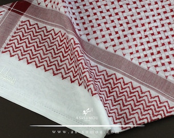May include: White and red patterned shemagh with a red border. The shemagh has a woven pattern and the brand name "diplomat" is embroidered on the fabric.