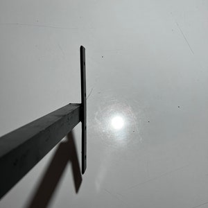 May include: Black metal shelf bracket with a rectangular shape and four holes for mounting.