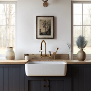 May include: A white farmhouse sink with a gold faucet and a wooden countertop. The sink is in a kitchen with dark blue cabinets and a window behind it.