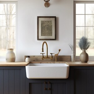 May include: A white farmhouse kitchen sink with a gold faucet and a wooden countertop. The sink is set against dark blue cabinets with a wood panel below.