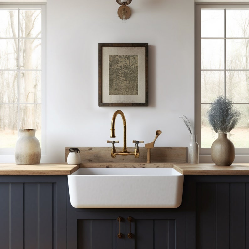 May include: A white farmhouse kitchen sink with a gold faucet and a wooden countertop. The sink is set against dark blue cabinets with a wood panel below.