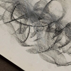 Op de afbeelding: Abstracte houtskooltekening op een witte achtergrond. De tekening bestaat uit overlappende lijnen en vormen, waardoor een gevoel van beweging en diepte ontstaat.
