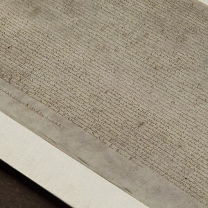 May include: A close-up of a historical document written in black ink on a parchment-like paper. The document is framed and displayed on a white mat.