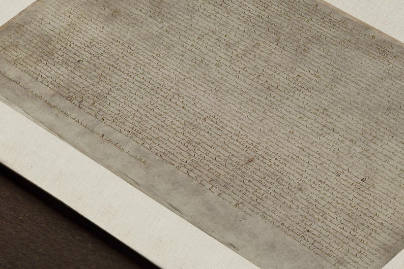 May include: A close-up of a historical document written in black ink on a parchment-like paper. The document is framed and displayed on a white mat.