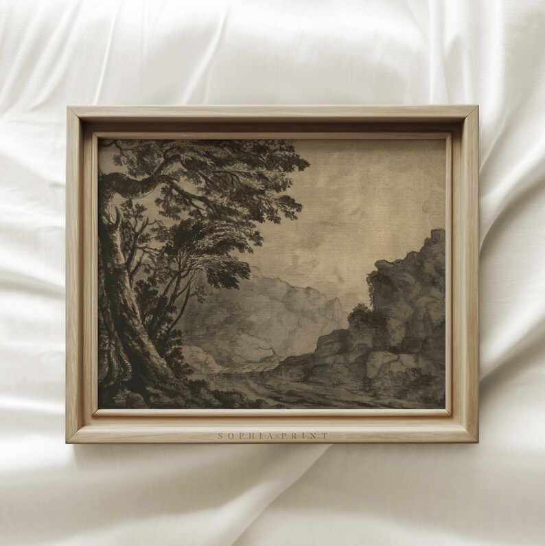 May include: A framed black and white landscape print of a mountain scene with a tree in the foreground. The print is on a textured canvas and has a subtle vintage feel. The frame is a light wood color. The print is signed "Sophia Print" in the bottom right corner.