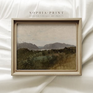 Puede incluir: Una pintura de paisaje vintage enmarcada que representa un valle fluvial con colinas onduladas y un cielo nublado. La pintura está en un marco de madera claro con un sutil tono marrón. El texto "SOPHIA PRINT" es visible en la parte inferior del marco.