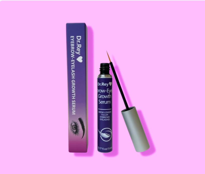 May include: Purple and silver bottle of Dr.Rey Brow-Eye Growth Serum with a black applicator brush. The bottle is labeled with the text "Grow Longer Fuller Eyebrows Eyelashes" and "0.17 fl oz/5 ml". The bottle is next to a purple box with the text "Dr.Rey Eyebrow-Eyelash Growth Serum".
