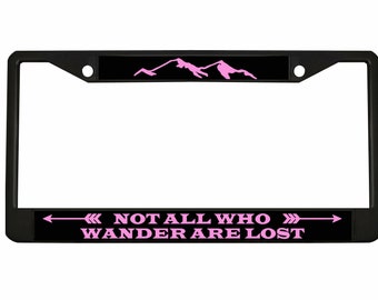 May include: Black metal license plate frame with a pink mountain silhouette and the text "NOT ALL WHO WANDER ARE LOST" with pink arrows on either side.